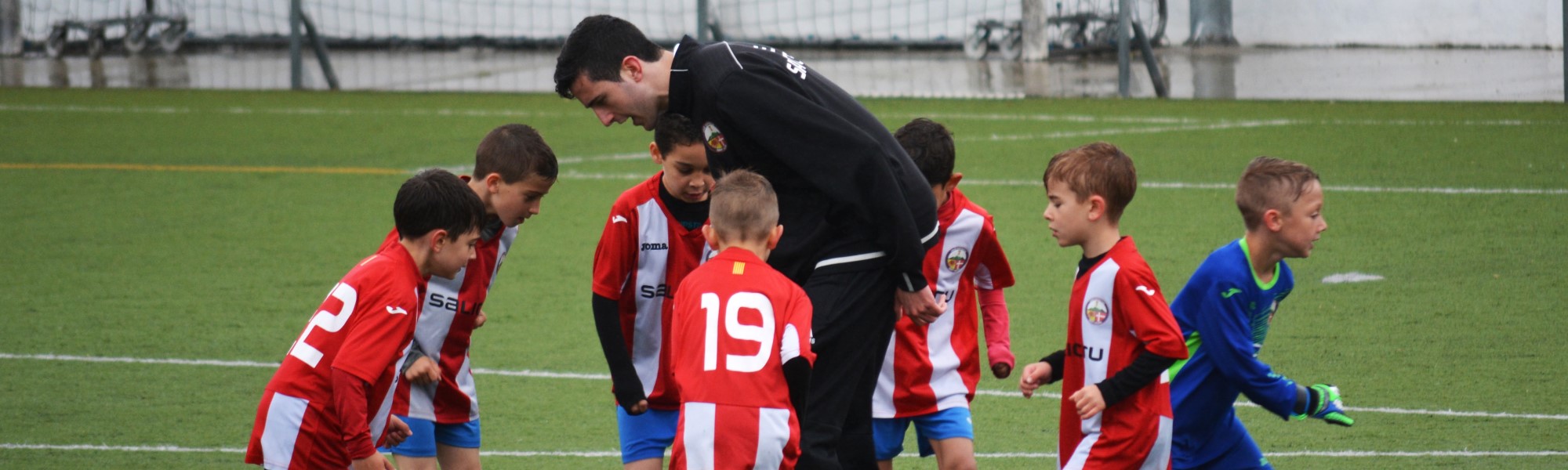 male coach helping young boys play soccer